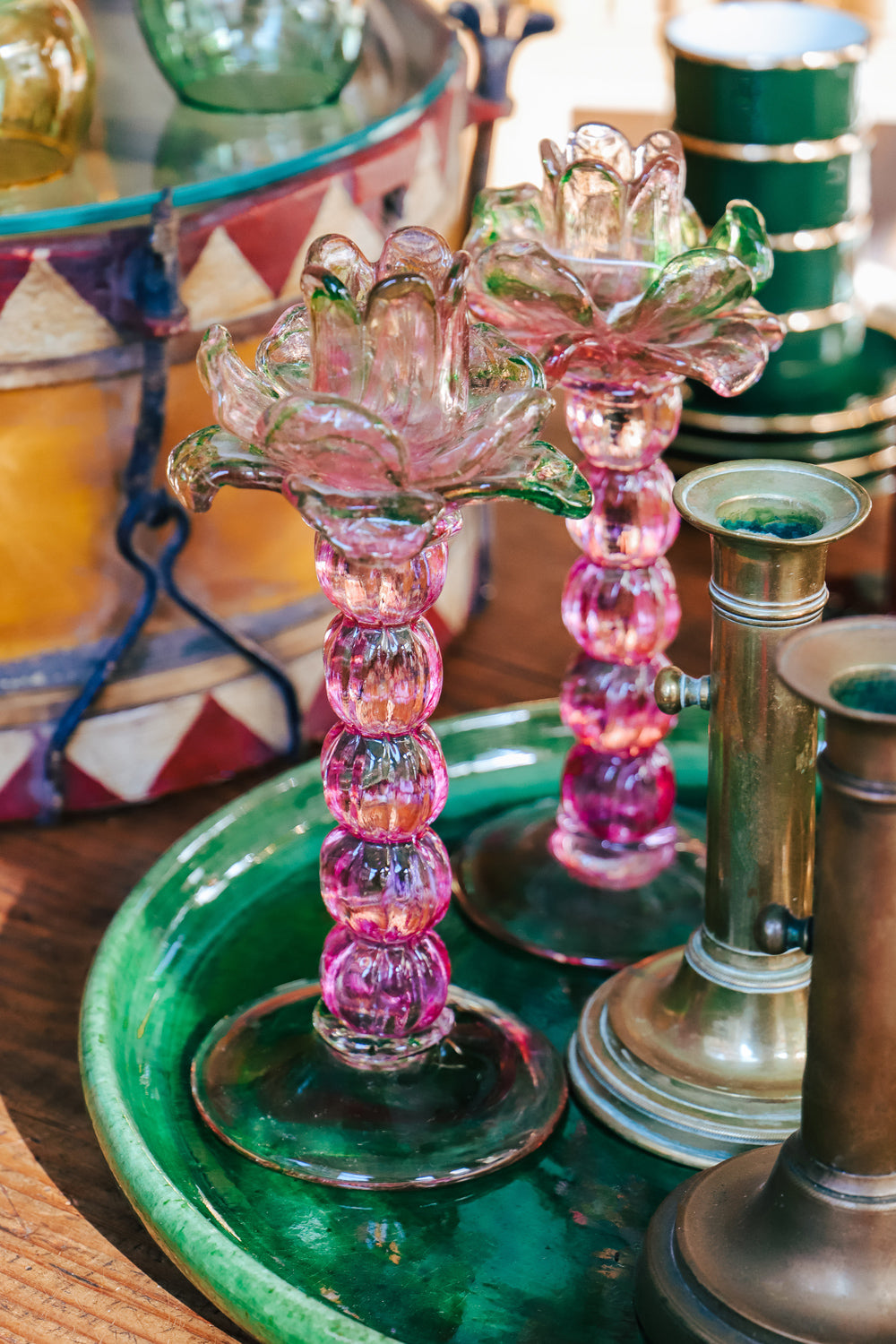 A pair of vintage Murano glass palm tree candle holders in green and pink colors, displayed on a emerald green platter in the store of Wildschut Antiques