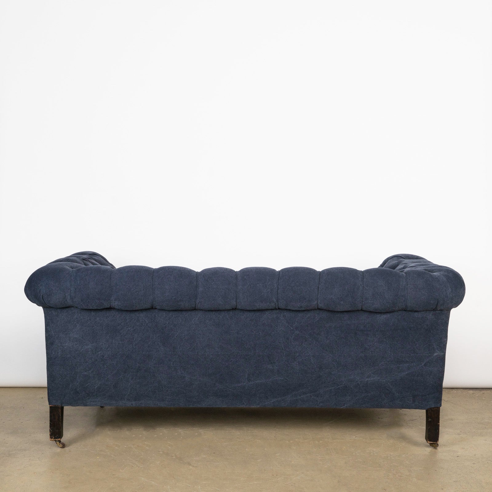 Backside of an elegantly tufted 19th-century French Napoleon III sofa, upholstered in stonewashed blue linen—available at Wildschut Antiques.