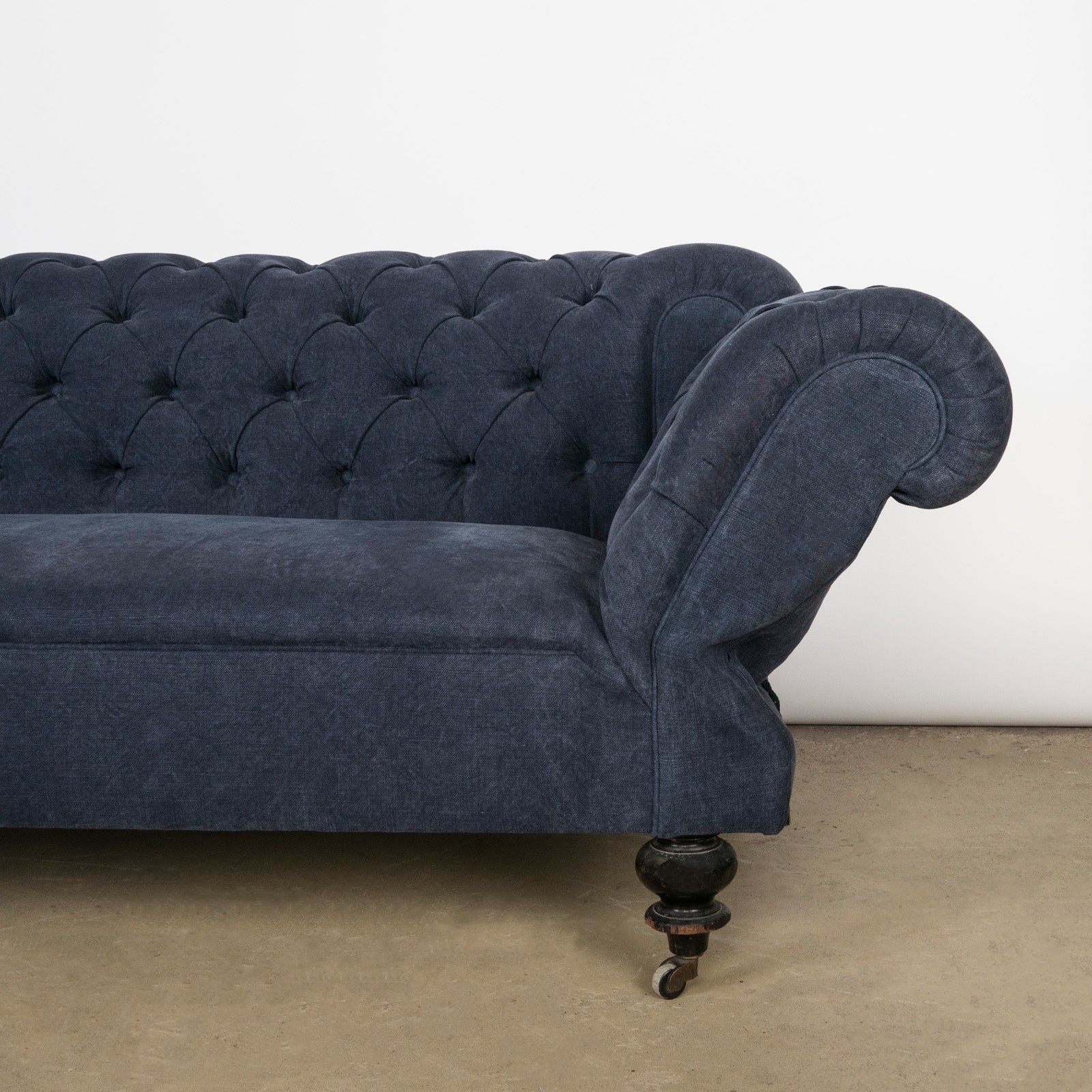 Close-up of the drop-end detail on an elegantly tufted 19th-century French Napoleon III sofa, upholstered in stonewashed blue linen—available at Wildschut Antiques.