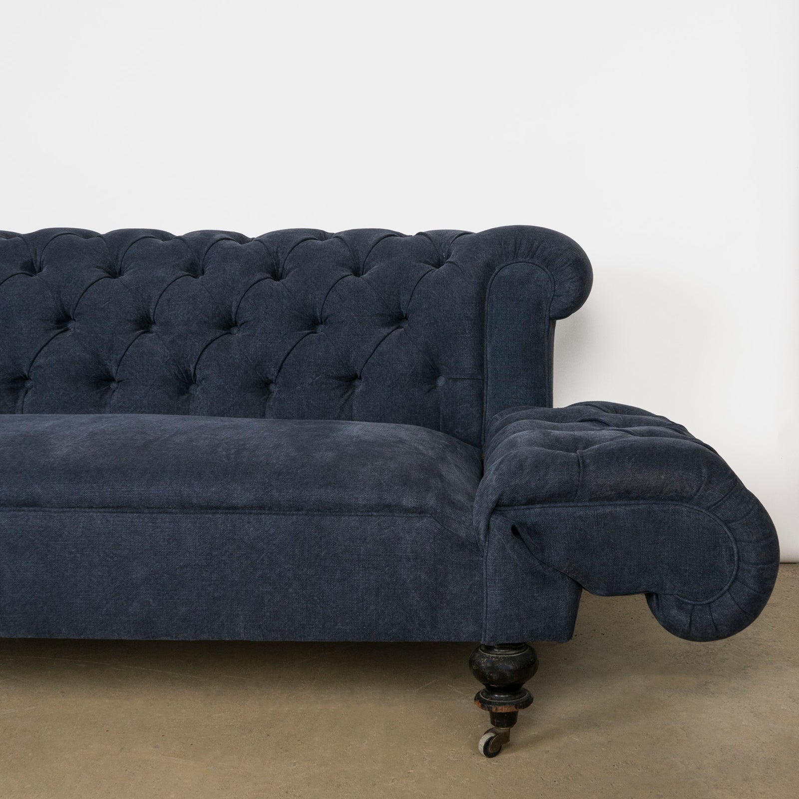 Close-up of the drop-end detail on an elegantly tufted 19th-century French Napoleon III sofa, upholstered in stonewashed blue linen—available at Wildschut Antiques.