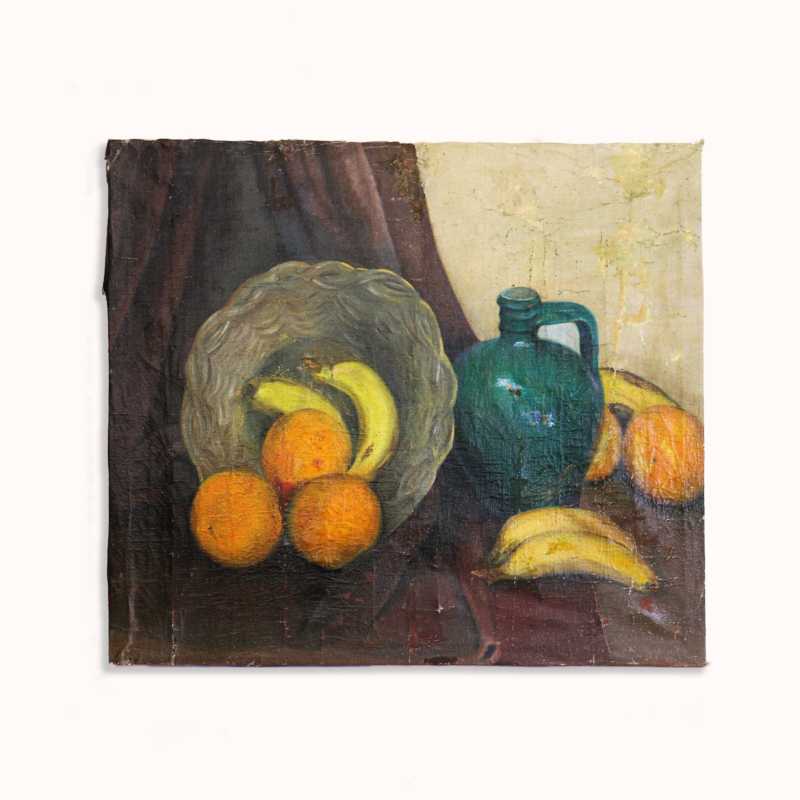 Decorative early 20th-century still life oil painting depicting a charming arrangement of oranges and bananas in a basket, alongside a green pitcher on the table, available at Wildschut Antiques