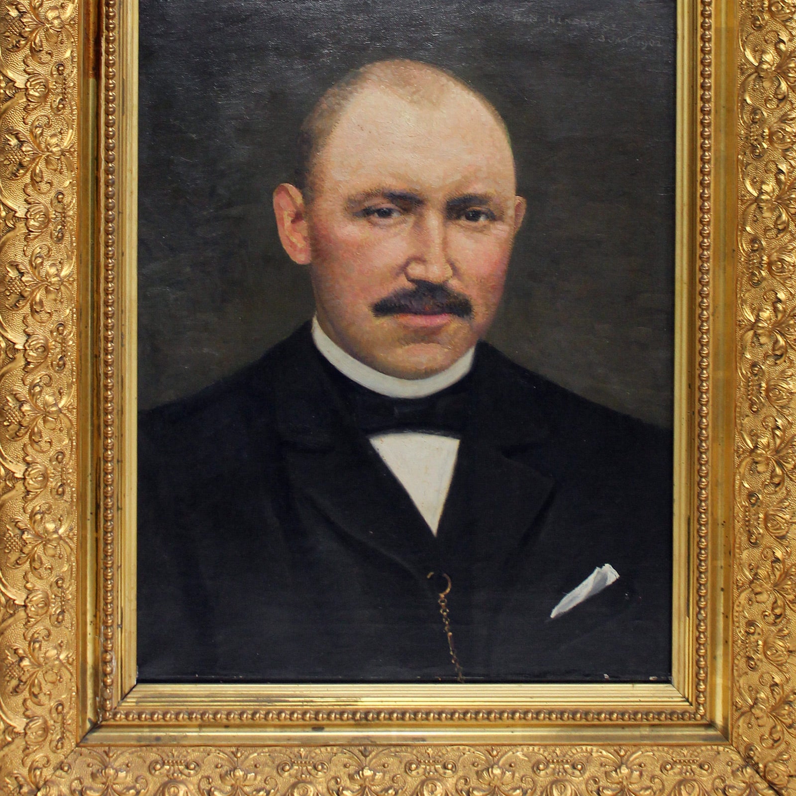 Close-up of an antique oil portrait of a gentleman with a moustache, bald head, and dark suit, expertly painted by W.N. Hendrikse, in a giltwood frame