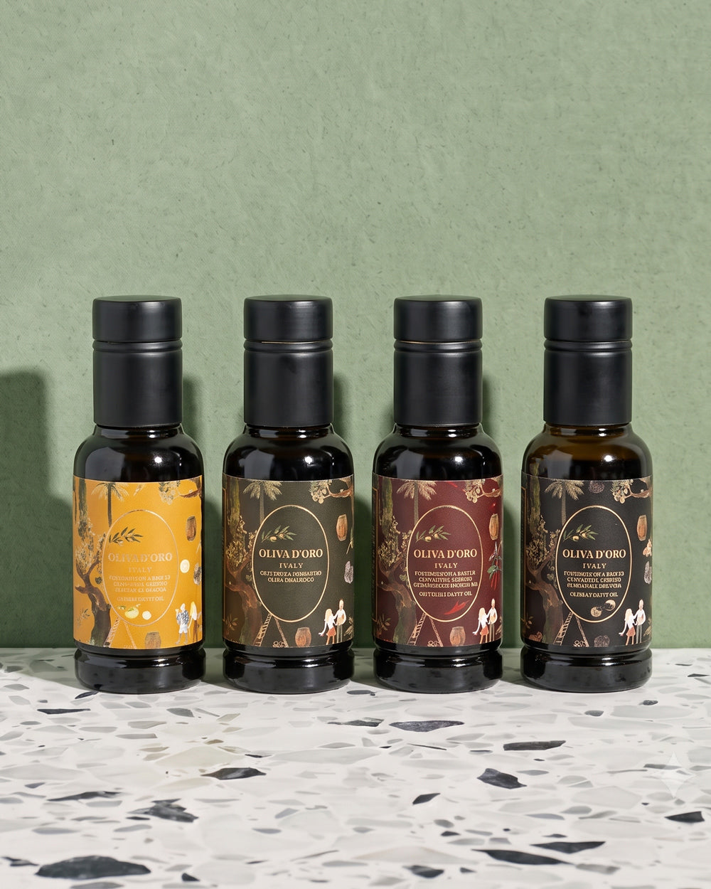 Four dark glass bottles of olive oil with black caps lined up on a speckled white and black countertop against a textured sage green wall. The labels are in yellow, brown, and burgundy tones with botanical illustrations and the brand name OLIVA D'ORO. Available via the Pantry Collection from Wildschut Antiques.