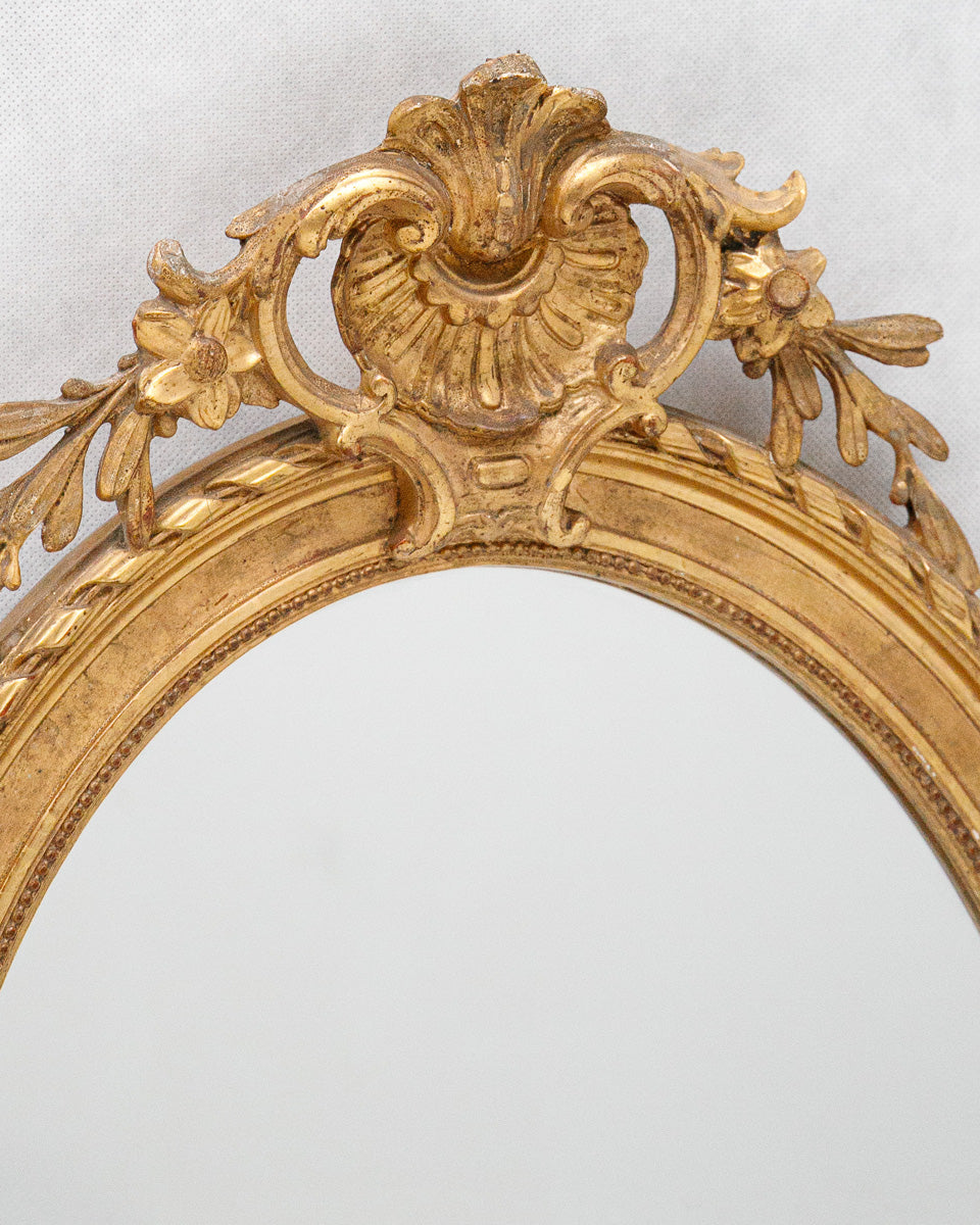 Close-up of a gold decorative antique mirror frame on a light gray background