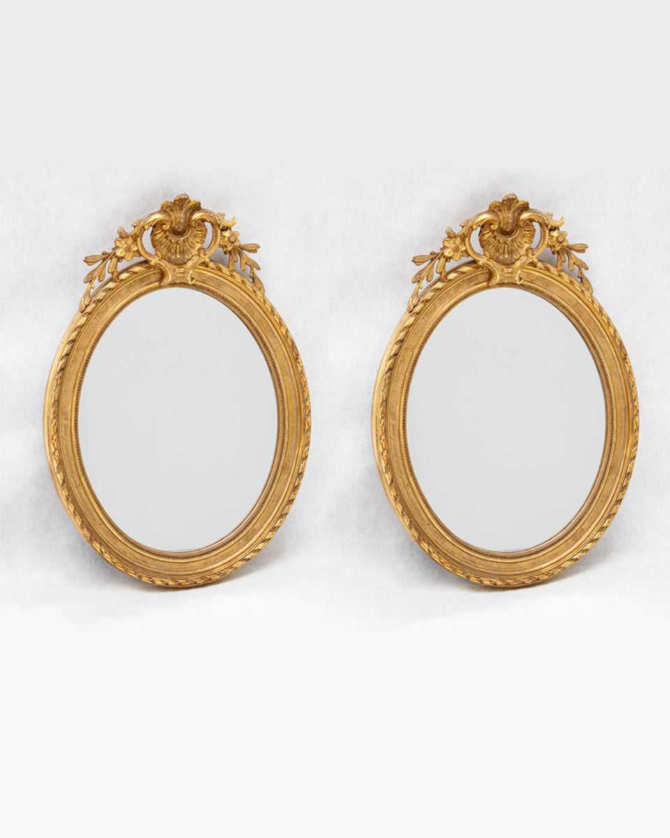 Two antique gold oval mirrors with decorative frames and small shell crests available at Wildschut Antiques