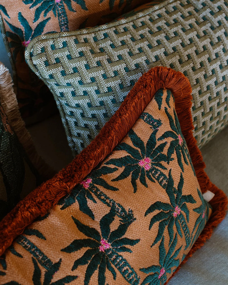 Two patterned cushions on a sofa, one with palm tree design and the other with geometric pattern, by Dutch brand Palais available via Wildschut Antiques.