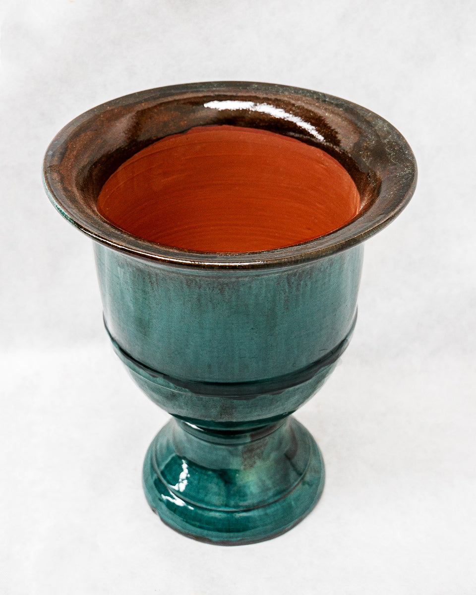Ceramic planter with brown interior and teal exterior on a white background