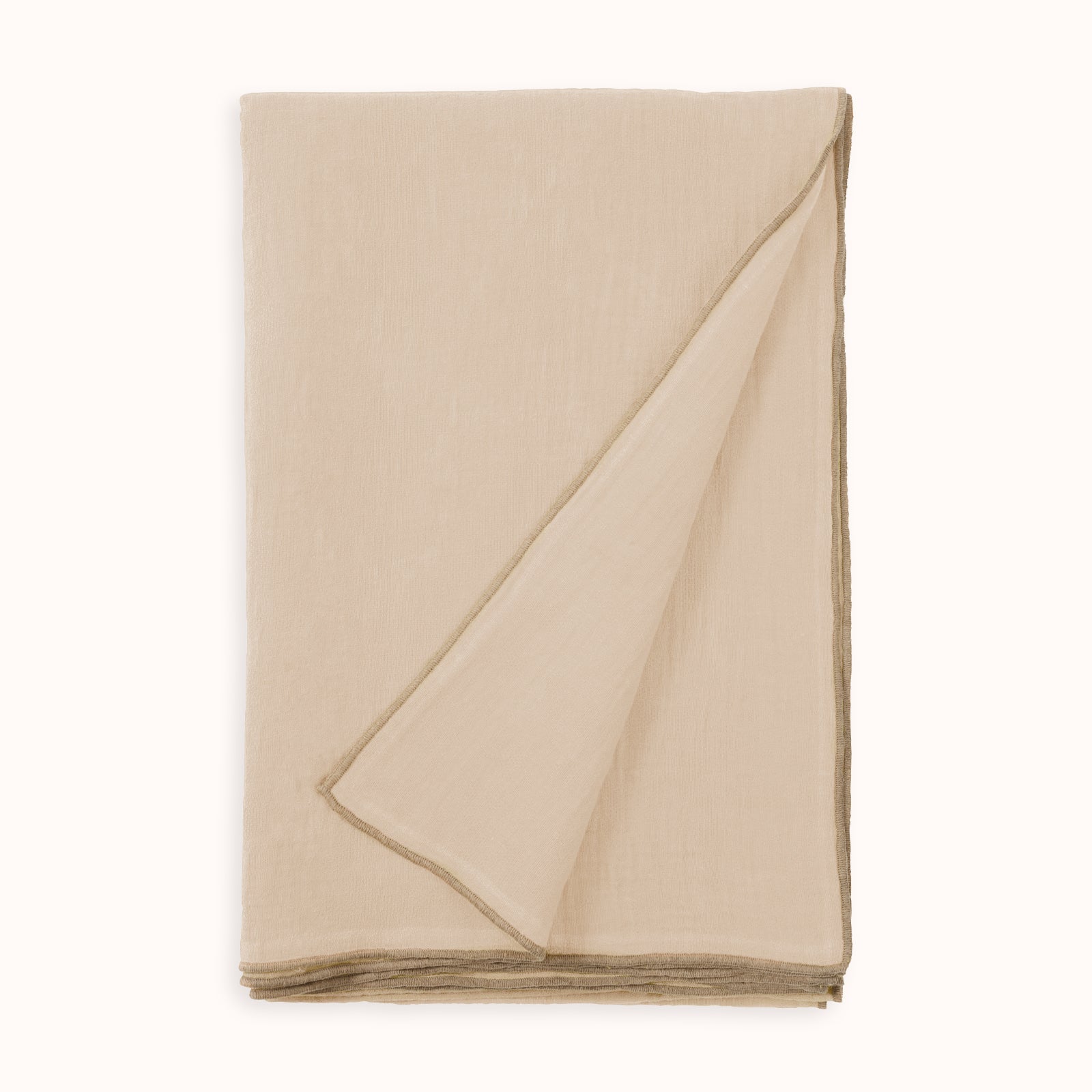 A soft pink beige-colored linen blend throw blanket with a subtle texture, folded neatly and available at Wildschut Antiques