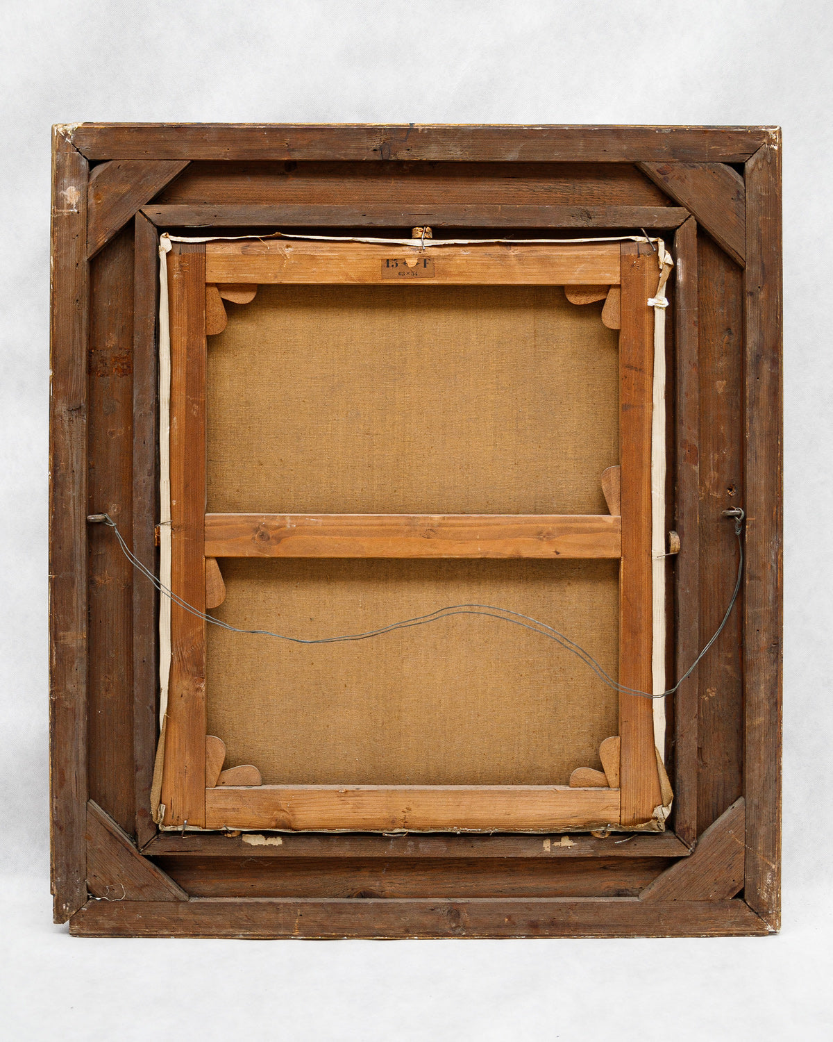 Back view of a wooden picture frame with a beige canvas inside on a white background