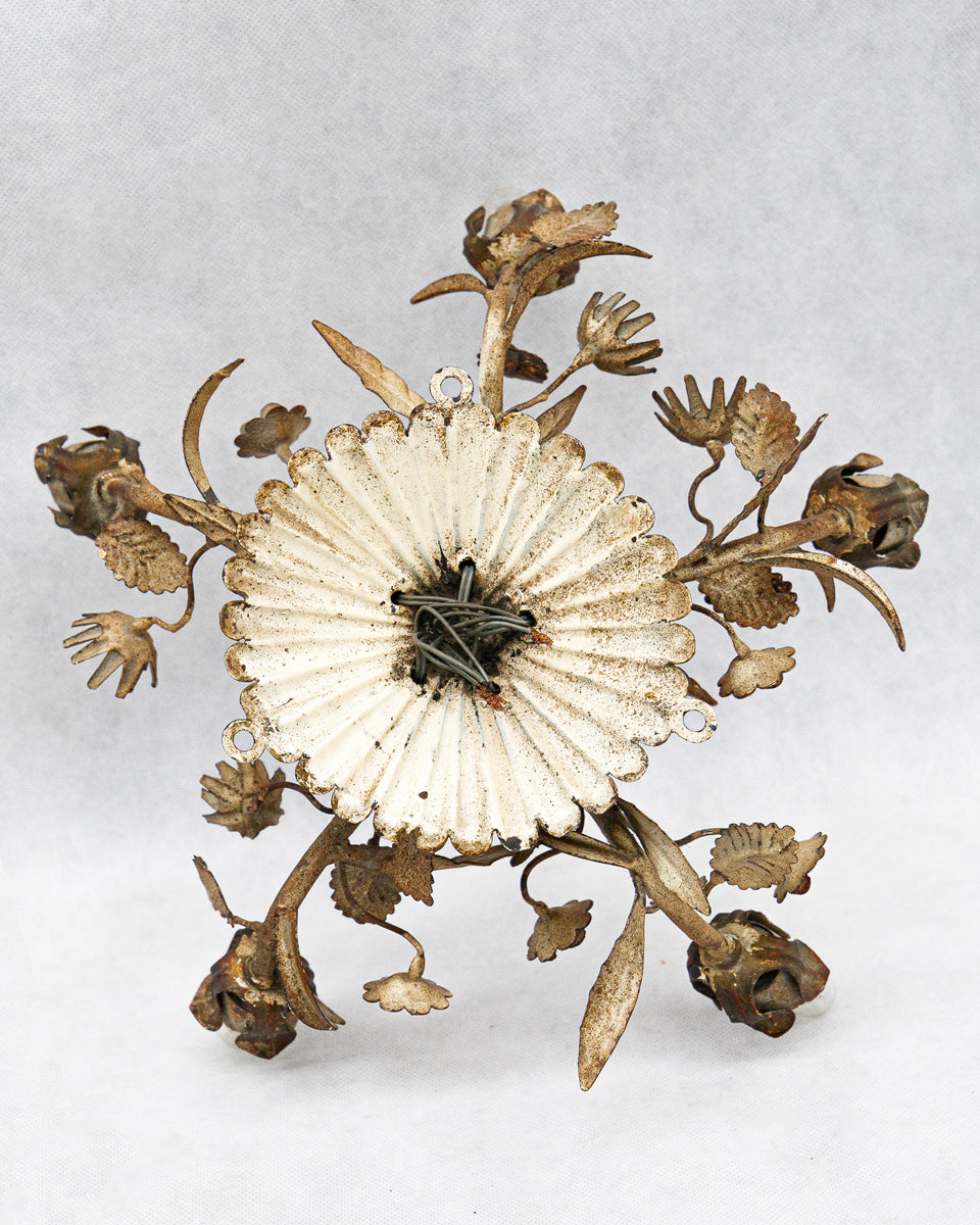 Backside of a decorative tole wall sconce or ceiling light with floral designs on a white background