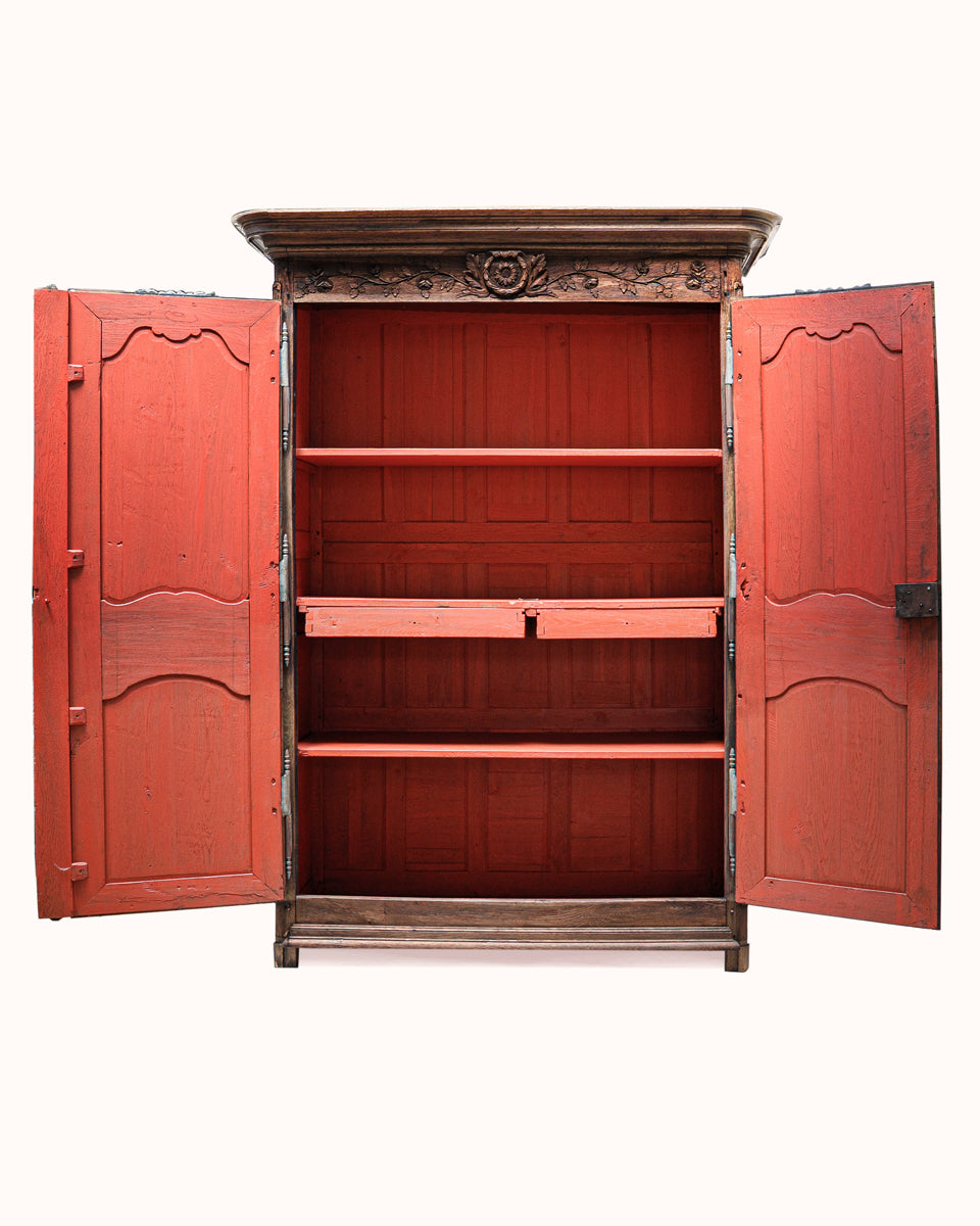 The interior of an antique French wooden armoire or marriage wardrobe featuring intricate carvings, shown against a white background.