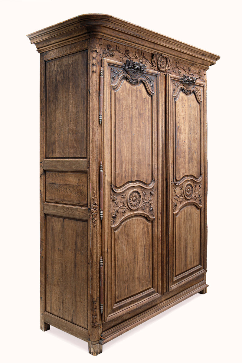 Antique French wooden wardrobe with intricate carvings on a white background
