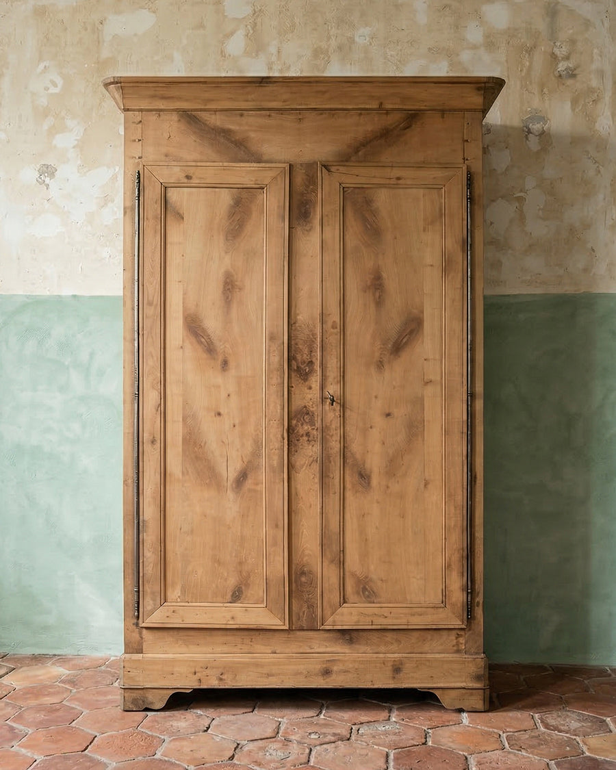 Antique French wooden wardrobe or Louis Philippe Armoire against a wall with a green and beige color scheme, available via Wildschut Antiques.