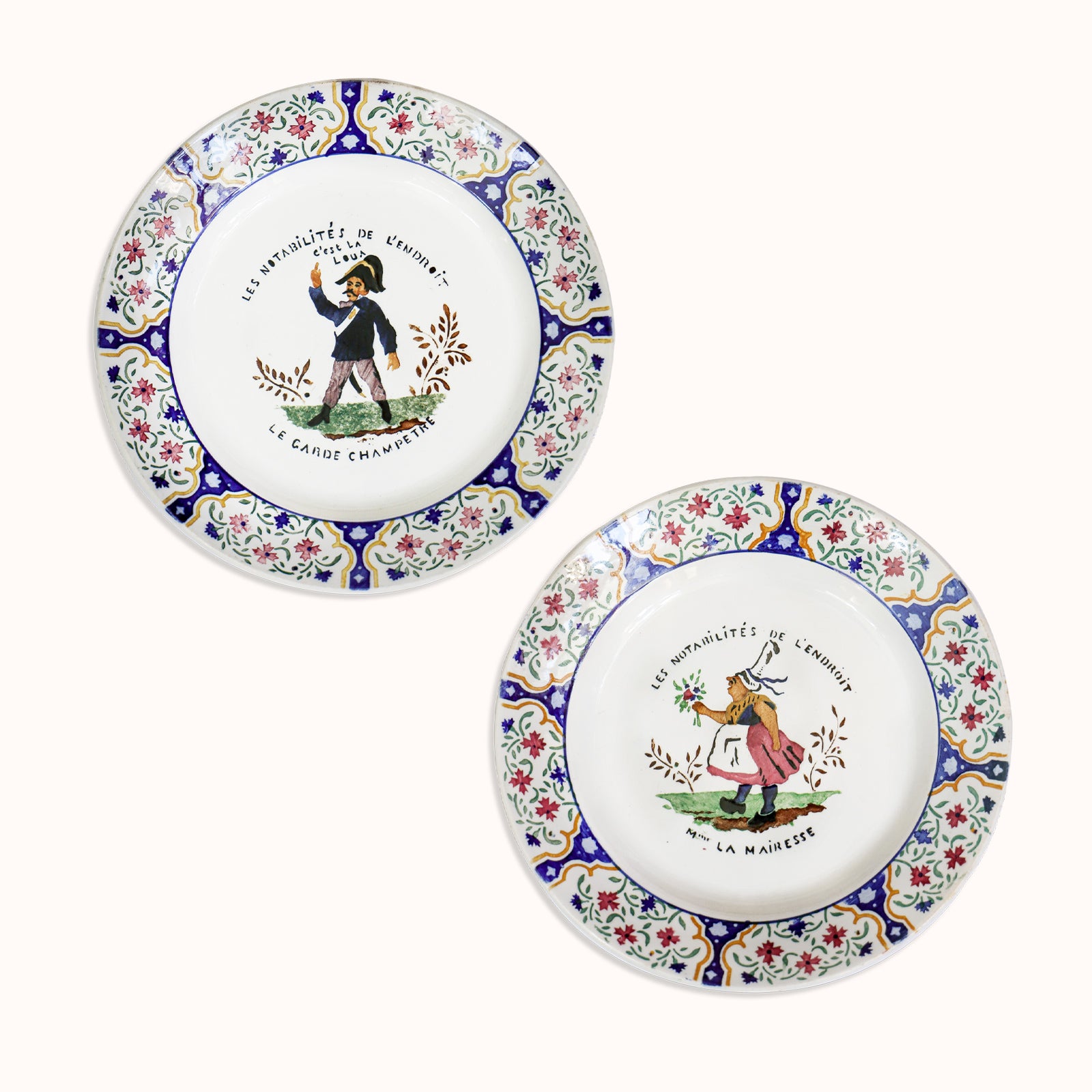 A set of two vintage Gien majolica ceramic plates with hand-painted depictions of a 'Garde Champére' and 'Madame La Mairesse' in a floral and colorful design, available at Wildschut Antiques