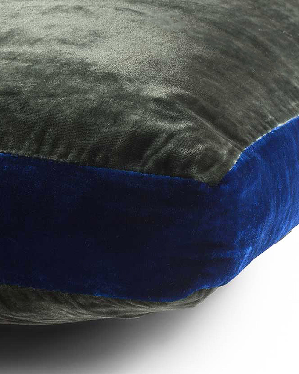 Close-up of a textured dark green silk velvet velour cushion with a dark blue border on a white background. Model James, designed by Monde Sauvage Paris, available at Wildschut Antiques.