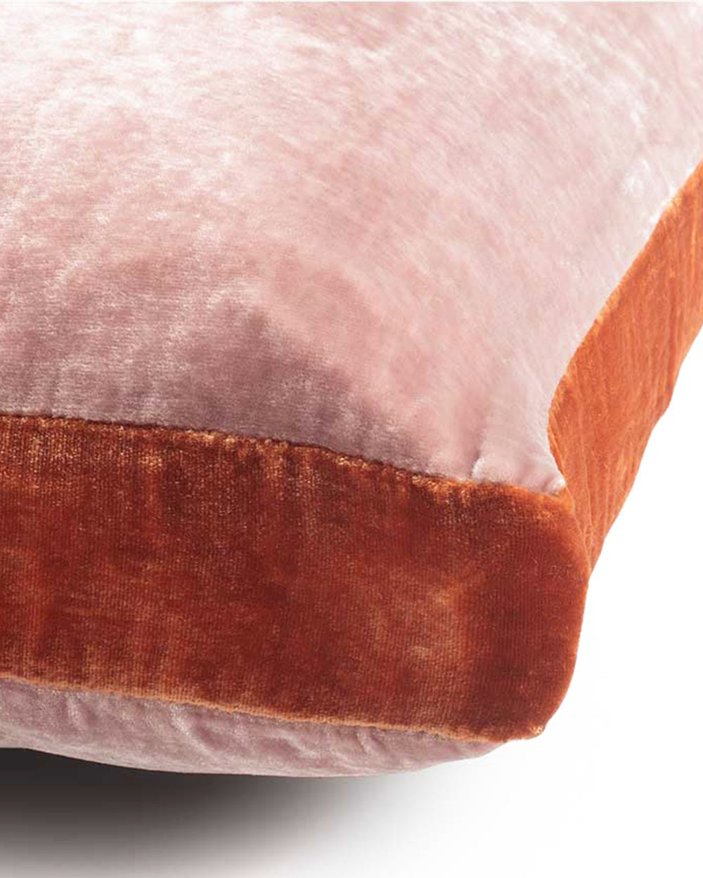 Close-up of a pink velvet velours pillow with a dark orange border on a white background. Model James, designed by Monde Sauvage Paris, available at Wildschut Antiques.