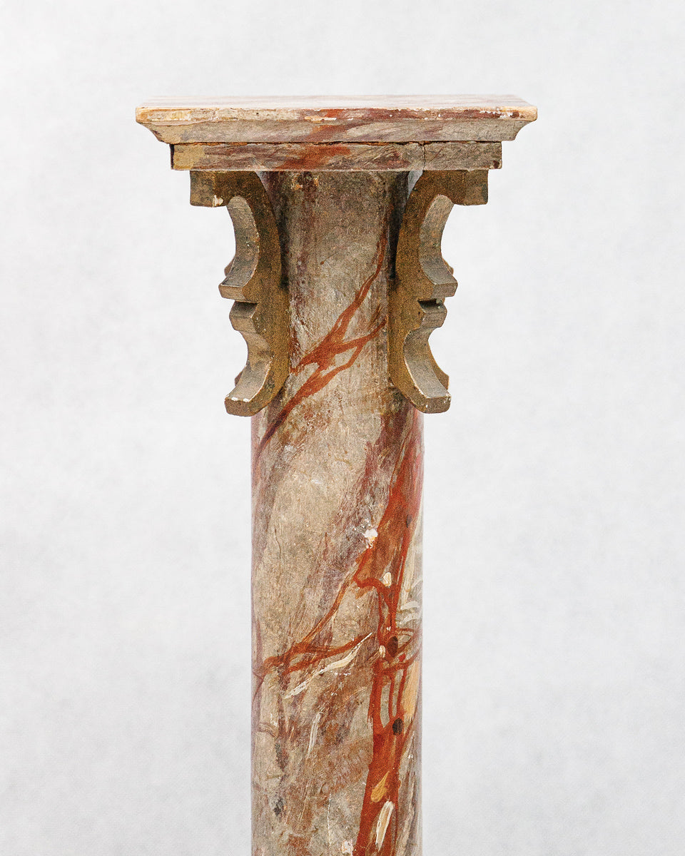 Close-up of a decorative faux marble wooden column or pedestal with intricate design on a white background