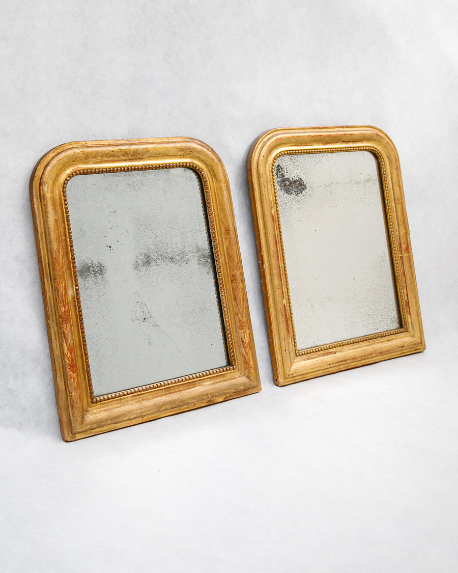 Two small antique French gold-framed Louis Philippe mirrors with foxed mirror glass on a white background, available at Wildschut Antiques.