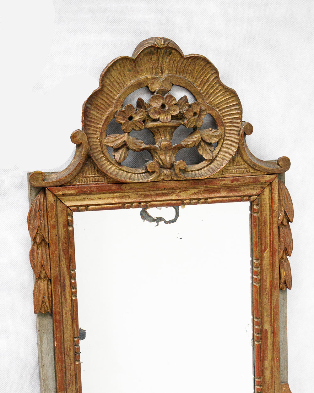 Detail of a decorative antique gold gilt wooden marriage mirror with intricate flower carvings on a white background, available via Wildschut Antiques