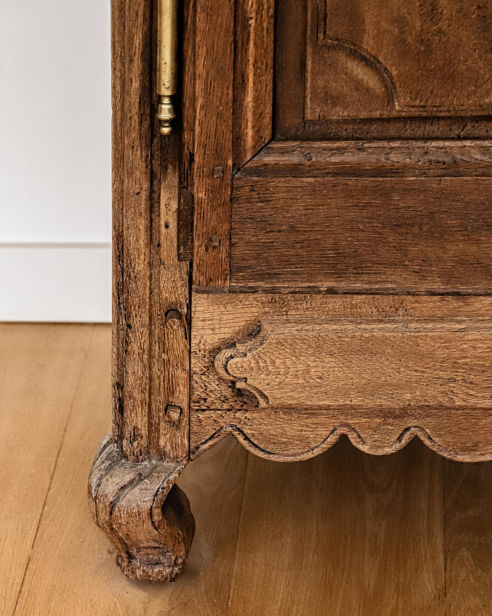 Detail of a leg of an antique French Louis XV style armoire with star shaped inlays on the doors, made of wood with a visible rustic finish