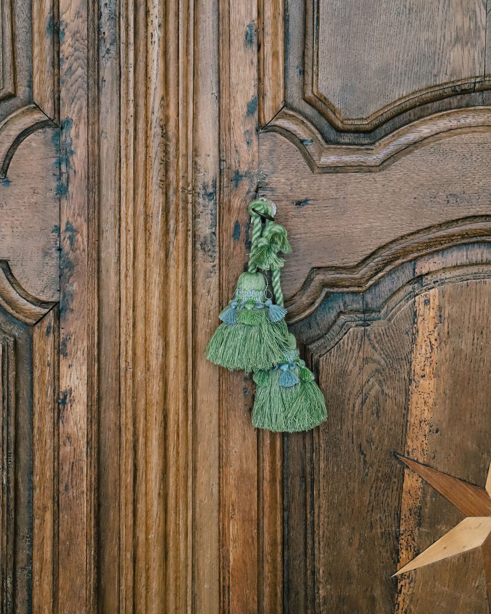 Close-up of an antique French Louis XV style armoire with star shaped inlays on the doors, made of wood with a visible rustic finish