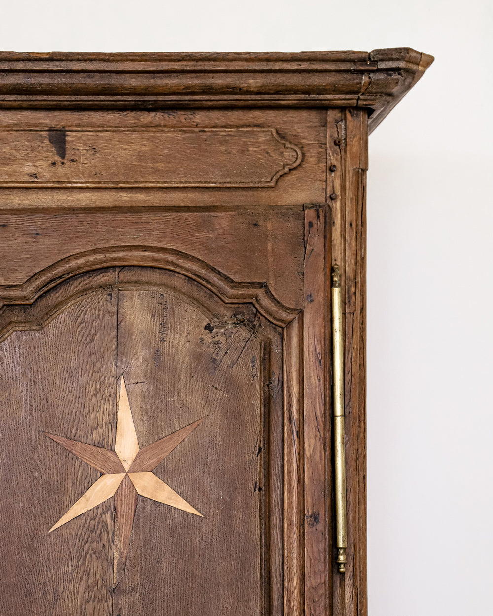 Detail of an antique French Louis XV style armoire with star shaped inlays on the doors, made of wood with a visible rustic finish