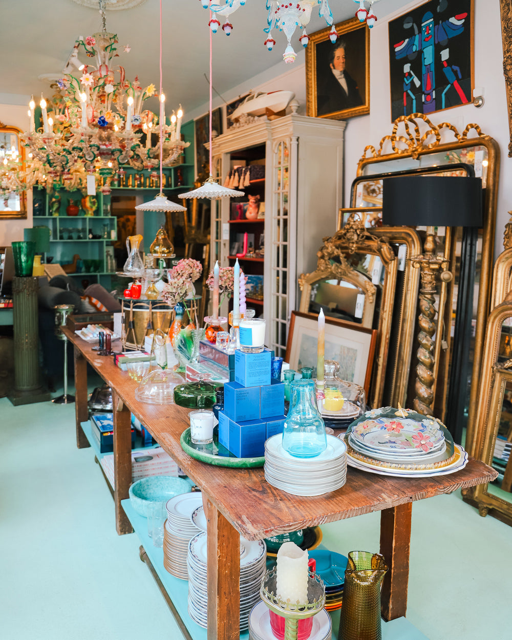 Inside Wildschut Antiques in the Jordaan district of Amsterdam, featuring golden antique mirrors, Murano chandeliers, and colorful decor
