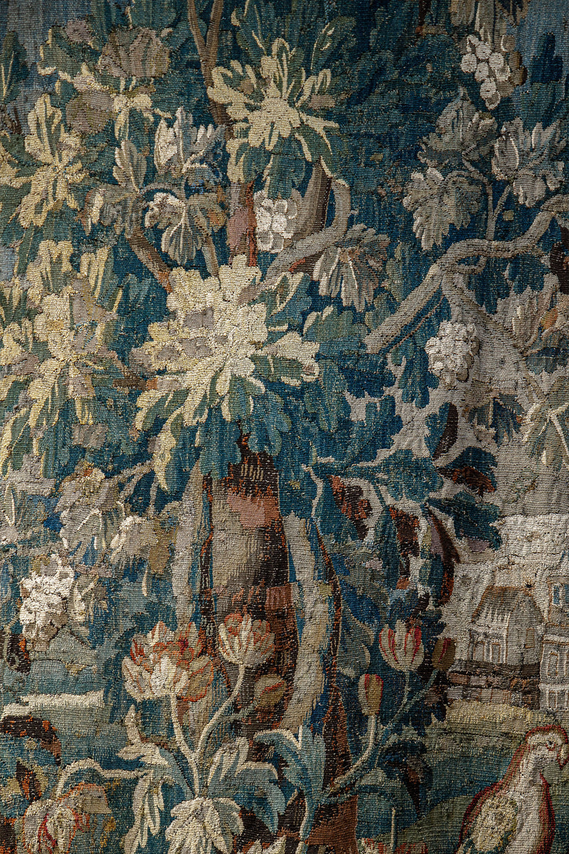 Close-up of a decorative 18th-century Verdure tapestry with a bird, a tree and foliage.