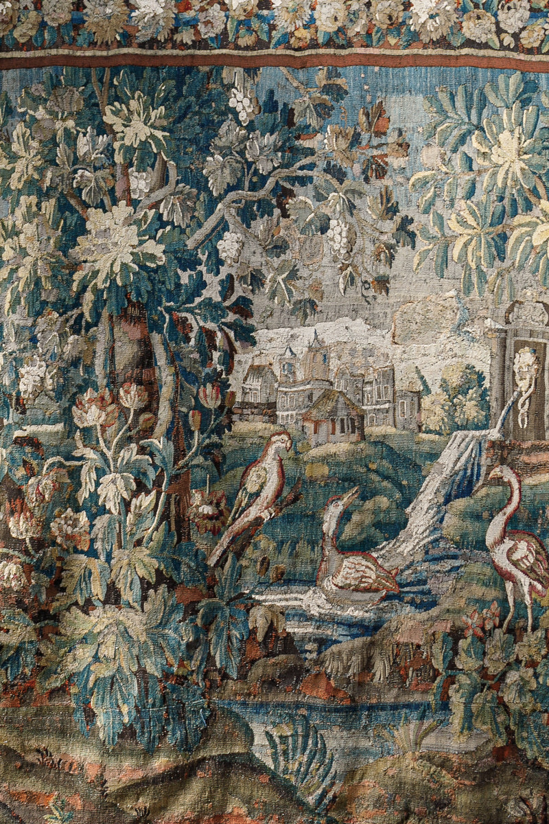 Close-up of a decorative 18th-century Verdure tapestry with birds, flowers, foliage and a landscape.