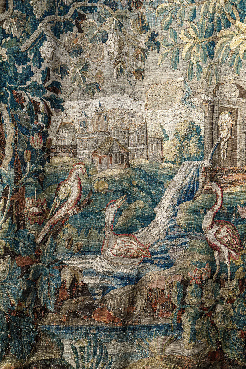 Close-up of a decorative 18th-century Verdure tapestry with birds, trees, and a landscape.