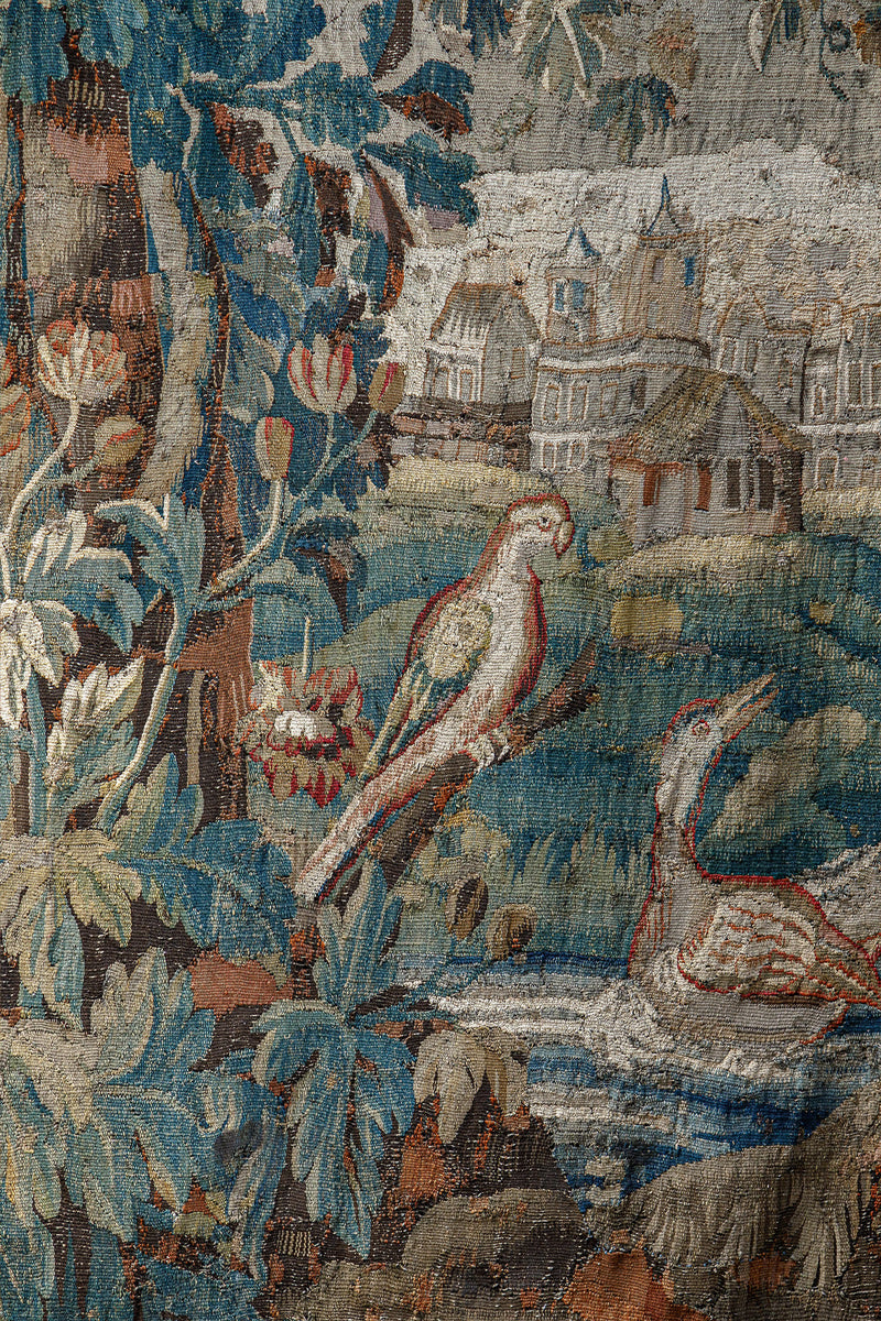 Close-up of a decorative 18th-century Verdure tapestry with birds, foliage, and a landscape.