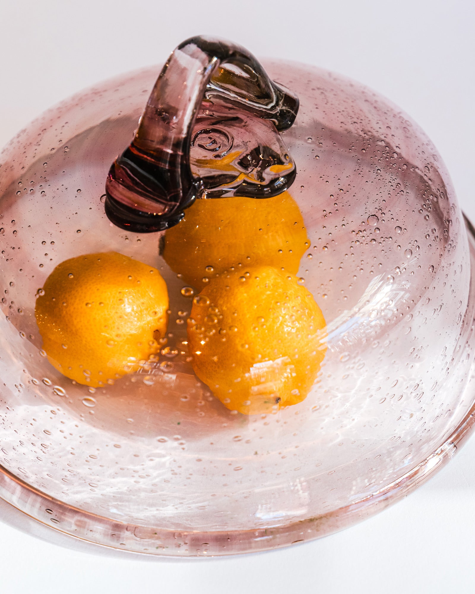 Close-up of a taupe-colored bubble glass bell dome by Biot, circa 1970s, displayed with three lemons.