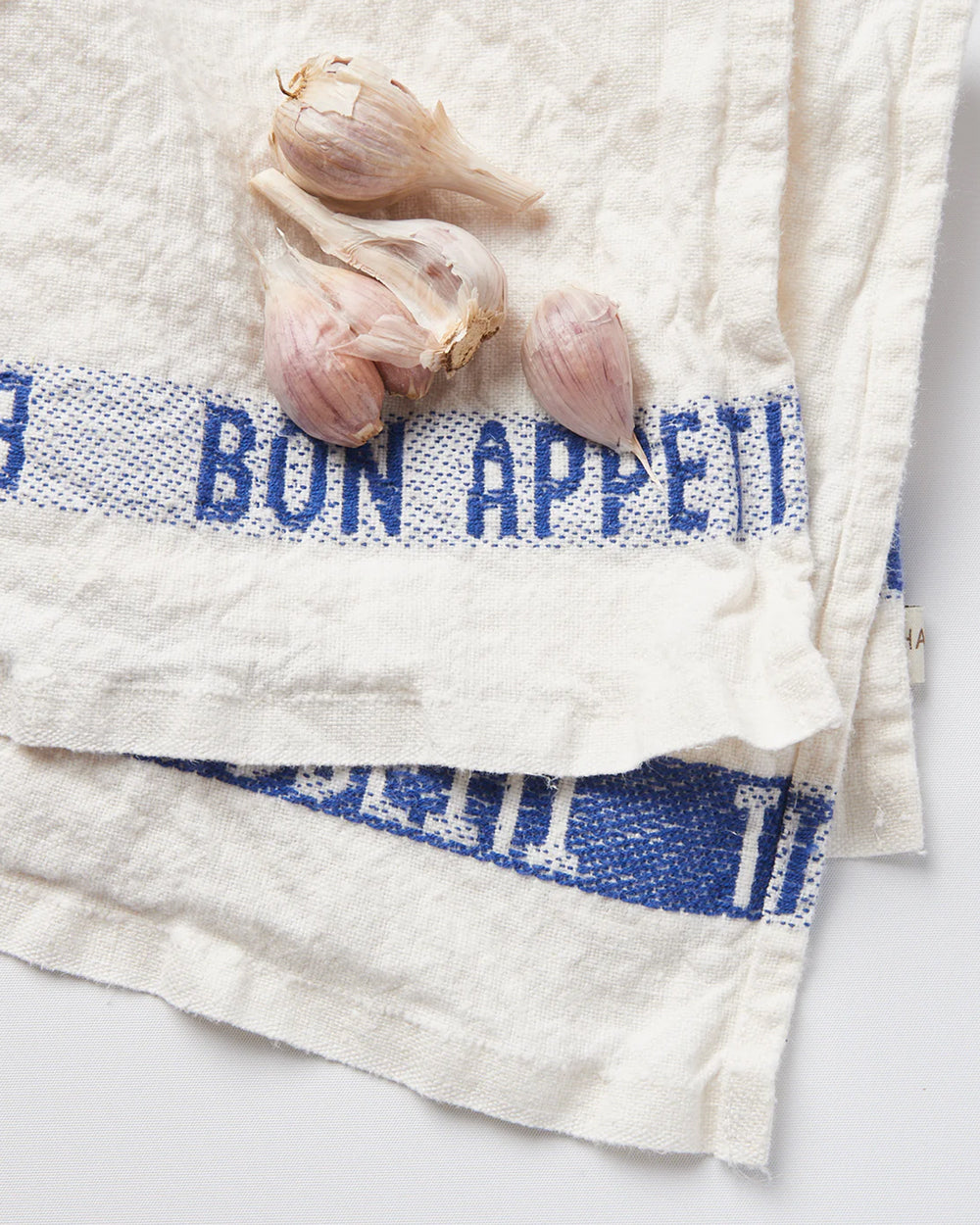 White linen dish towel with 'BON APPÉTIT' embroidered in blue along the edges, by Charvet Editions, available at Wildschut Antiques