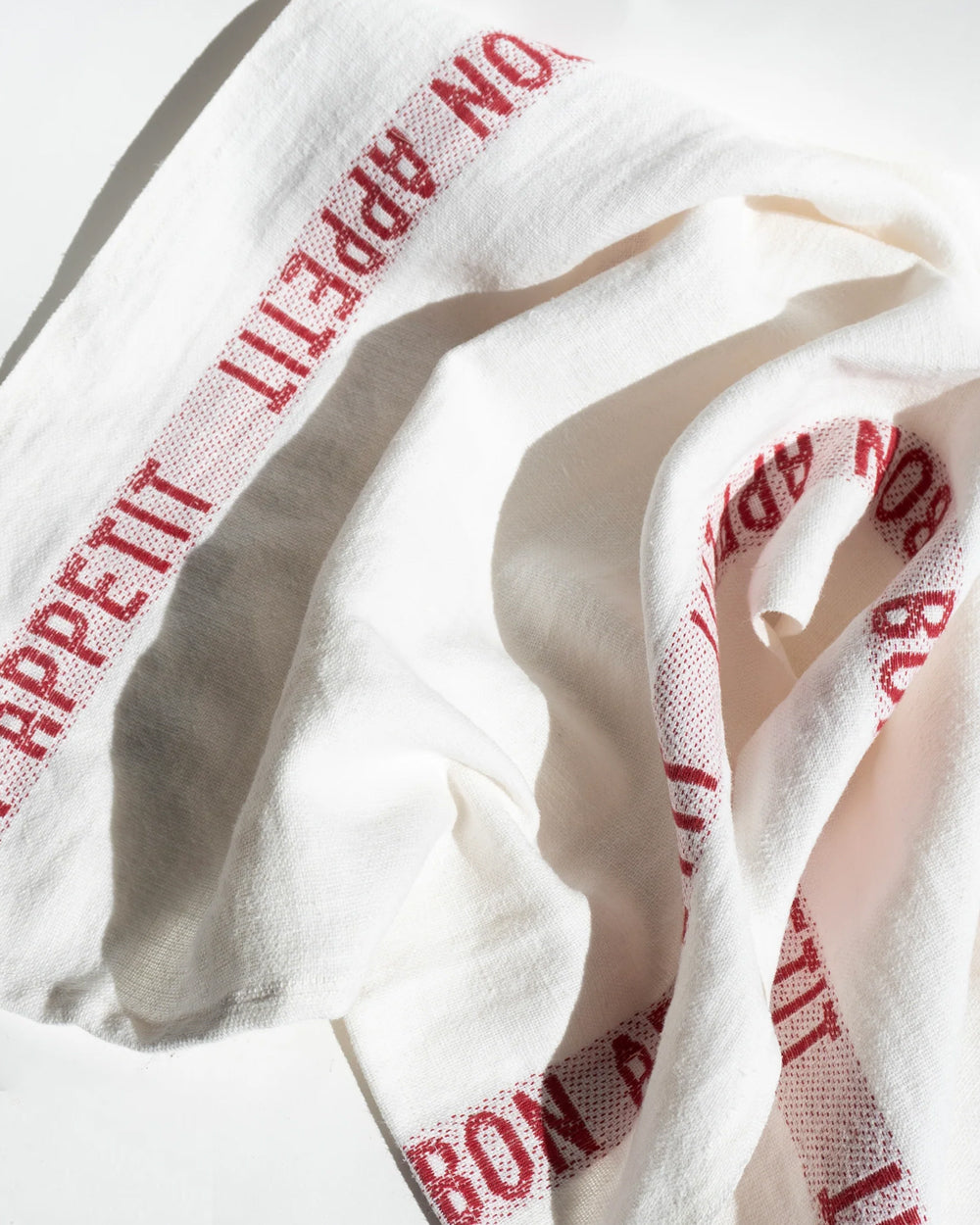 White linen dish towel with 'BON APPÉTIT' embroidered in red along the edges, by Charvet Editions, available at Wildschut Antiques