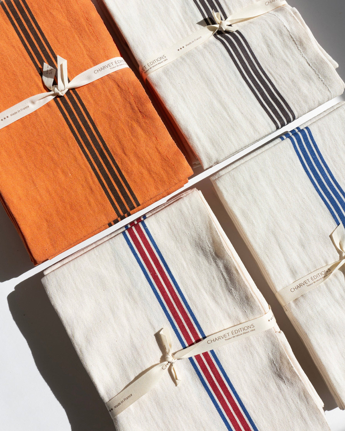 A collection of folded dish towels with stripes by Charvet Editions available at Wildschut Antiques