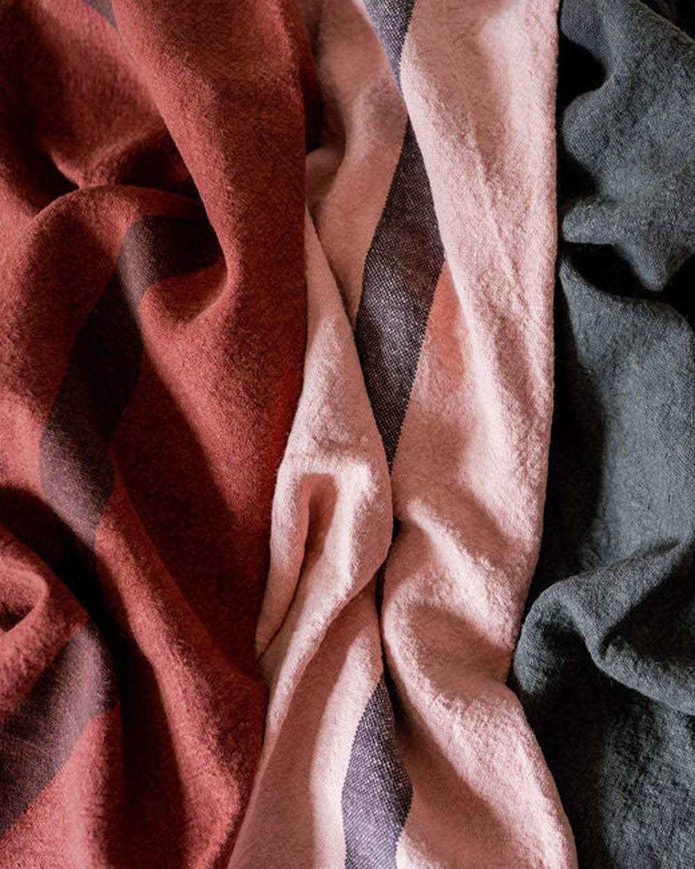 A petale pink, red and dark grey linen dish towel with a vertical stripe detail in the center by Charvet Editions and available at Wildschut Antiques