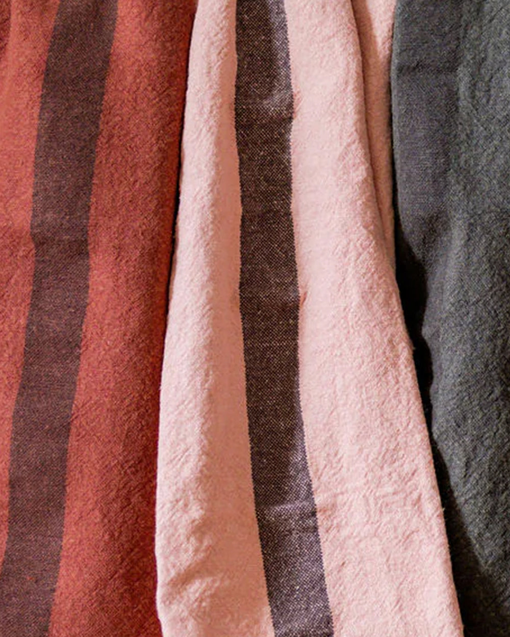 A petale pink, red and dark grey linen dish towel with a vertical stripe detail in the center by Charvet Editions and available at Wildschut Antiques