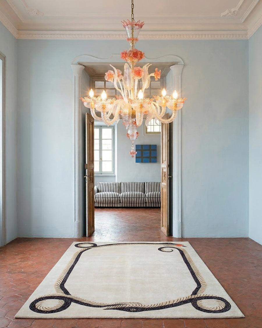 Luxurious interior with a Venetian Murano glass chandelier, rug, and sofa in a well-lit room. Items via Wildschut Antiques.