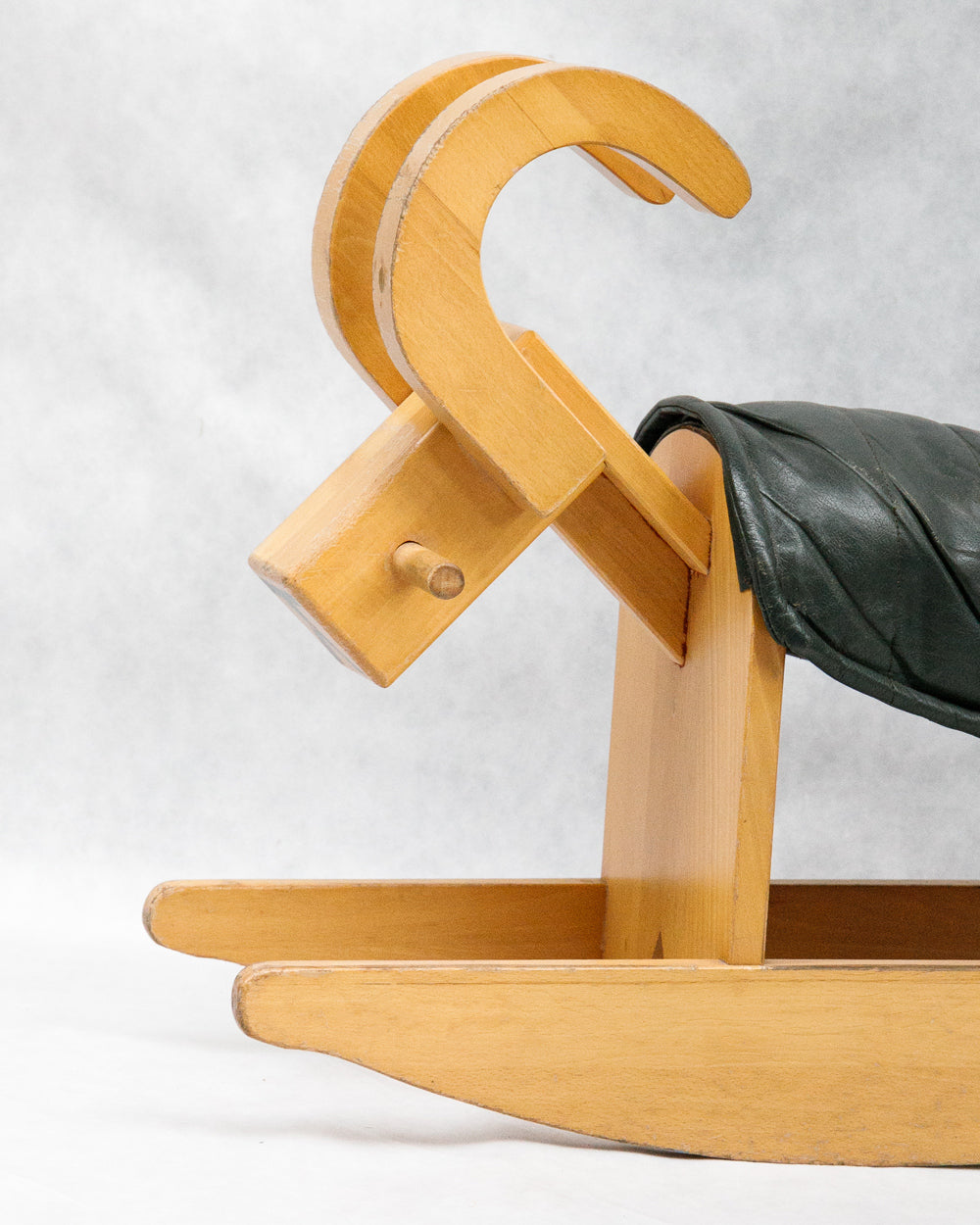 Close-up of a vintage wooden rocking billy goat with a dark green leather deck