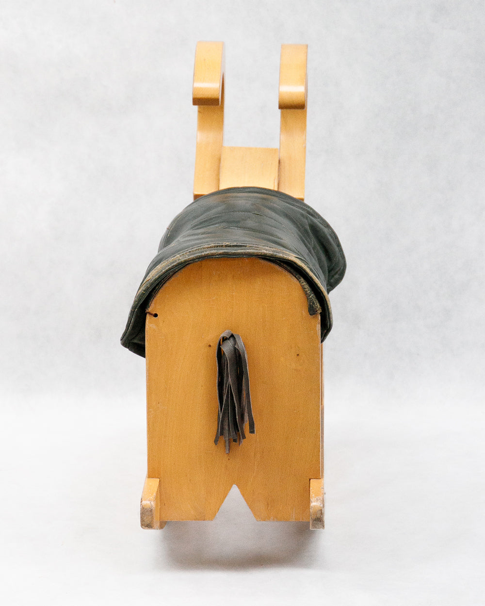 Close-up of a vintage wooden rocking billy goat with a dark green leather deck
