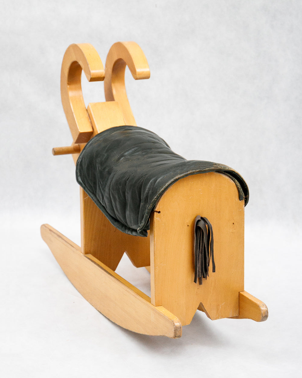 Backside of a vintage wooden rocking billy goat with a dark green leather deck