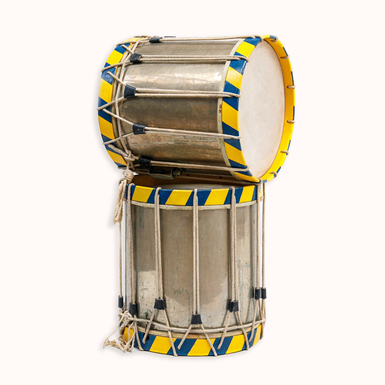 Two vintage drums with blue and yellow paint, and silver drum heads, bound by ropes, available at Wildschut Antiques