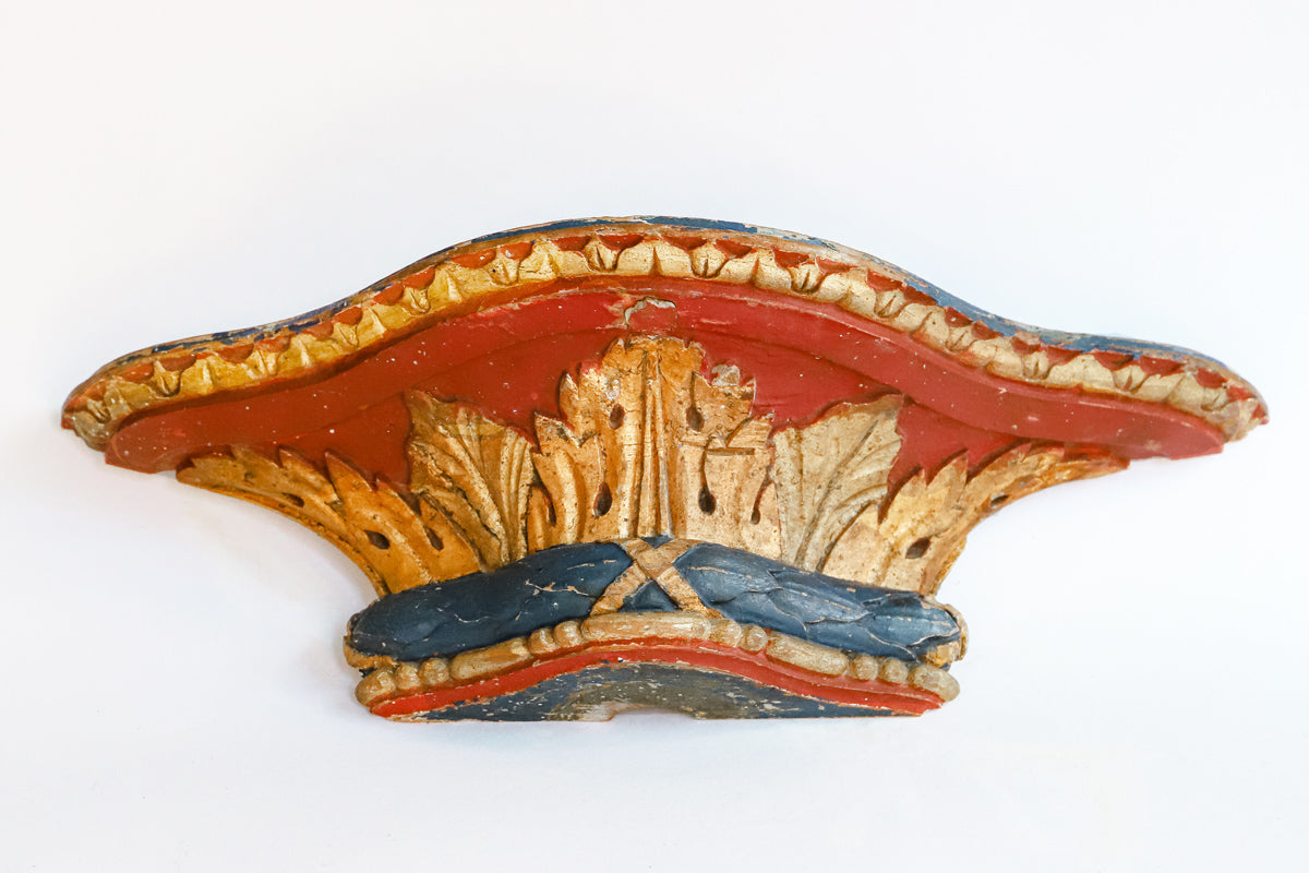 A small antique French carved and gilded wall bracket, with original paint and a richly aged patina in red, blue, and gold tones.
