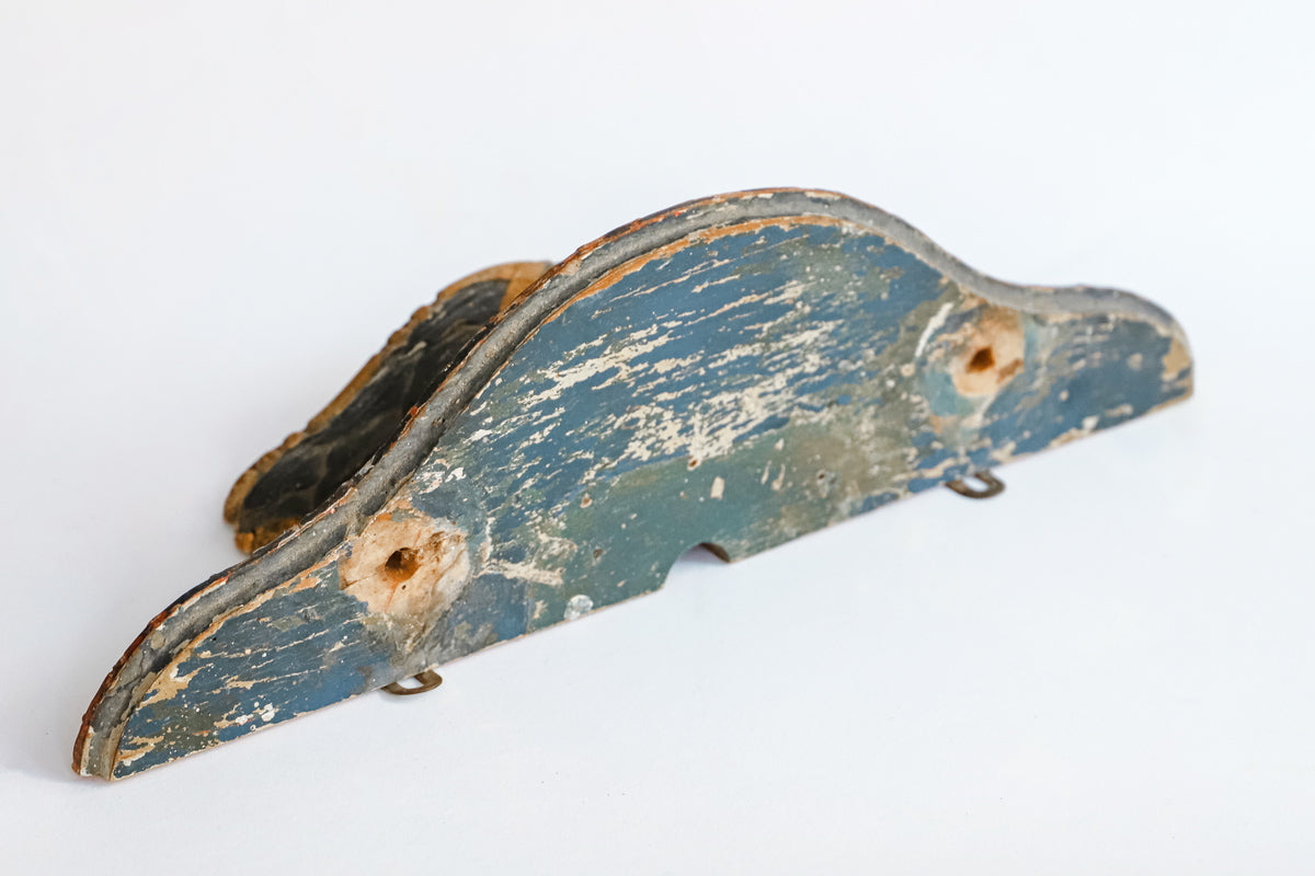 Detail of a small antique French carved and gilded wall bracket, with original paint and a richly aged patina in red, blue, and gold tones.