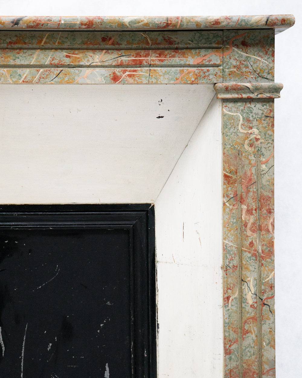 Close-up on an 19th century antique French fake painted marble fireplace with a colorful pattern on a white background, right corner
