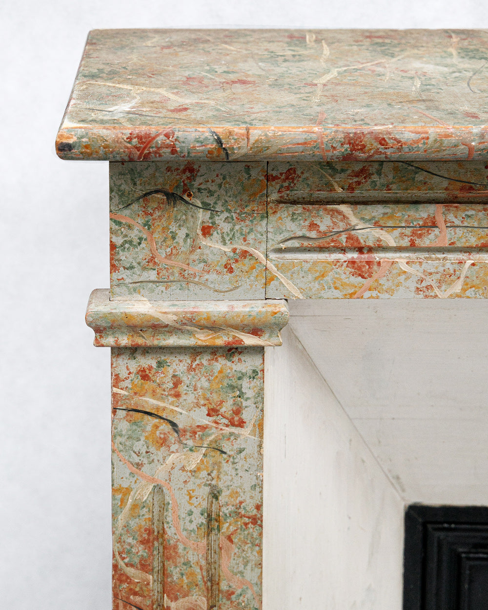 Close-up on an 19th century antique French fake painted marble fireplace with a colorful pattern on a white background