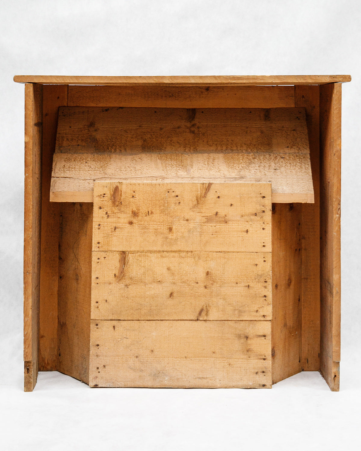 The wooden backside of a 19th-century French antique wooden fireplace with faux marble painting in a colorful pattern on a white background.