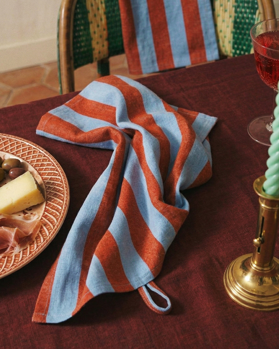 Striped red and blue towel on a table with food and a mint green swirl candle.