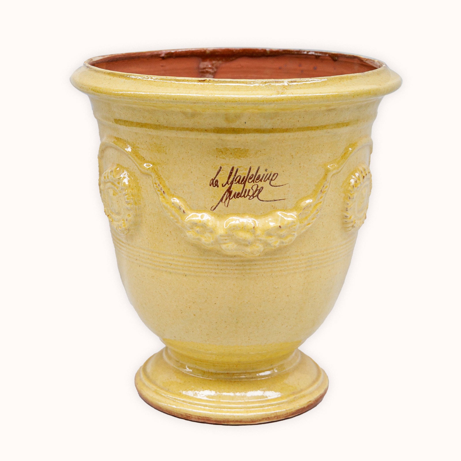 Yellow ceramic French Anduze pot with decorative elements and a signature on a white background available at Wildschut Antiques