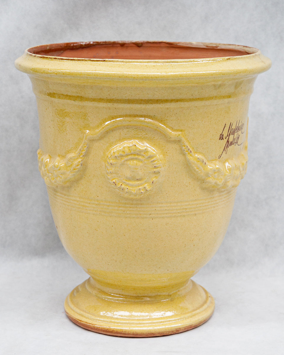 Yellow ceramic French Anduze pot with decorative elements and a signature on a white background available at Wildschut Antiques
